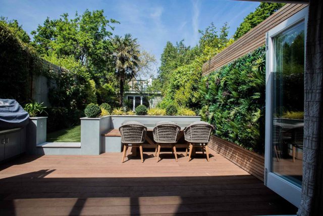 A family garden with terrace constructed with Design Clad from London Stone and VistaGreen artificial green wall panels to enhance a small well-loved garden.