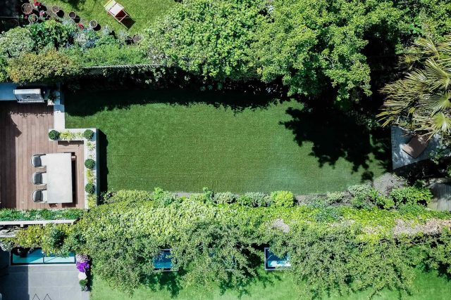 A family garden with terrace constructed with Design Clad from London Stone and VistaGreen artificial green wall panels to enhance a small well-loved garden.