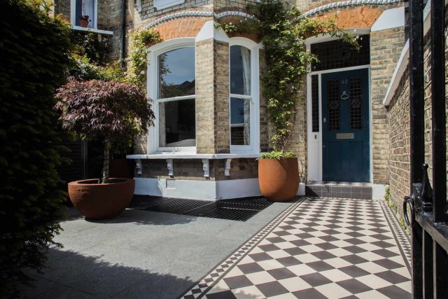 A family garden with terrace constructed with Design Clad from London Stone and VistaGreen artificial green wall panels to enhance a small well-loved garden.