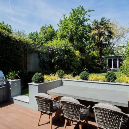 A family garden with terrace constructed with Design Clad from London Stone and VistaGreen artificial green wall panels to enhance a small well-loved garden.