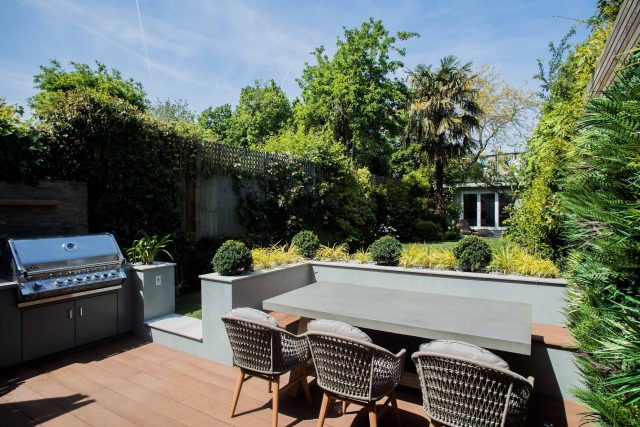 A family garden with terrace constructed with Design Clad from London Stone and VistaGreen artificial green wall panels to enhance a small well-loved garden.