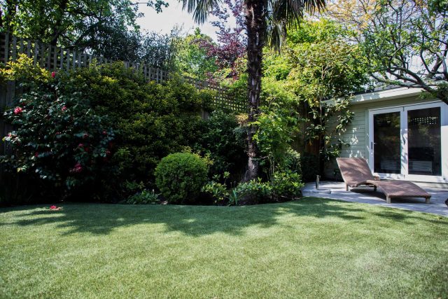 A family garden with terrace constructed with Design Clad from London Stone and VistaGreen artificial green wall panels to enhance a small well-loved garden.