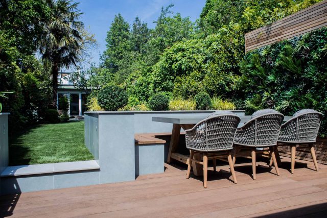 A family garden with terrace constructed with Design Clad from London Stone and VistaGreen artificial green wall panels to enhance a small well-loved garden.