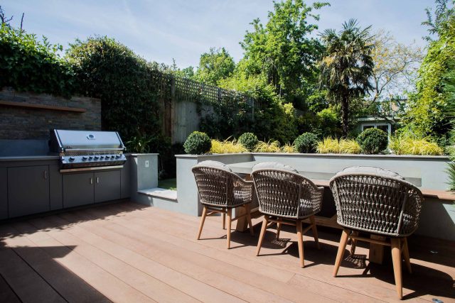 A family garden with terrace constructed with Design Clad from London Stone and VistaGreen artificial green wall panels to enhance a small well-loved garden.