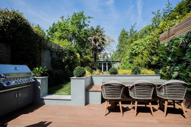 A family garden with terrace constructed with Design Clad from London Stone and VistaGreen artificial green wall panels to enhance a small well-loved garden.