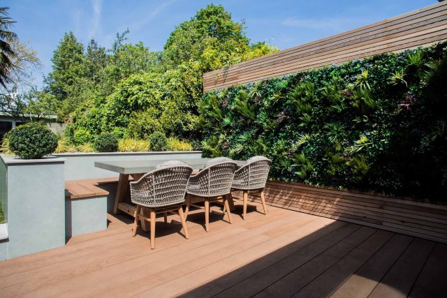 A family garden with terrace constructed with Design Clad from London Stone and VistaGreen artificial green wall panels to enhance a small well-loved garden.