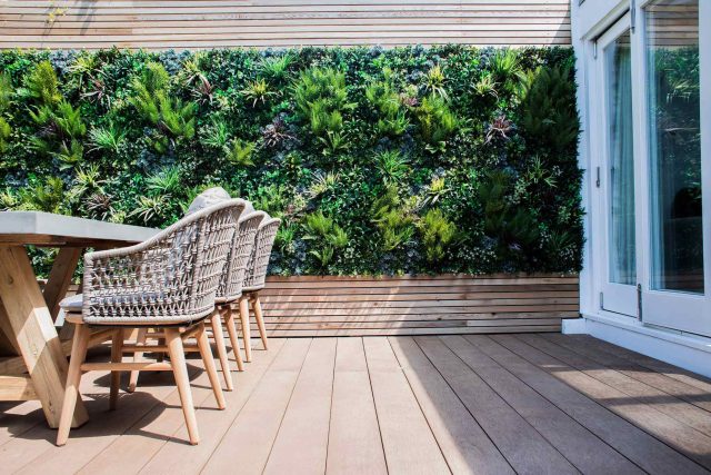 A family garden with terrace constructed with Design Clad from London Stone and VistaGreen artificial green wall panels to enhance a small well-loved garden.