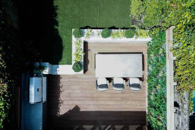 A family garden with terrace constructed with Design Clad from London Stone and VistaGreen artificial green wall panels to enhance a small well-loved garden.