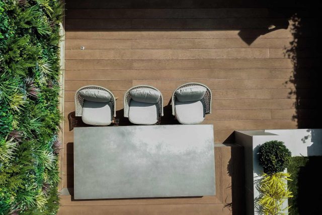 A family garden with terrace constructed with Design Clad from London Stone and VistaGreen artificial green wall panels to enhance a small well-loved garden.