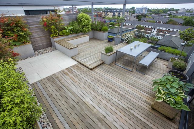 Roof Terrace garden Design for a penthouse apartment King's Cross development, expanse decking storage benches, planters, cedar deck seating area outdoor room.