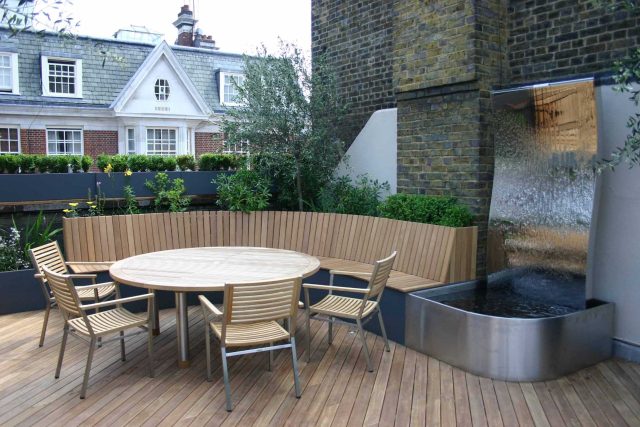 Contemporary Roof Terrace garden designer in Baker Street Marylebone, a stunning water feature curved bench cladded in iroko to create an illusion of space.