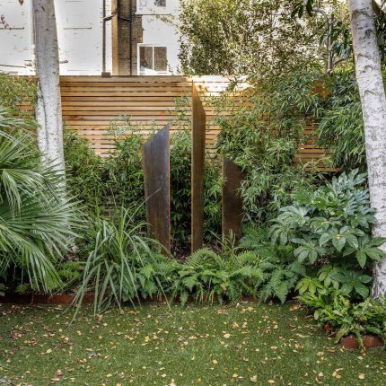 Small, contemporary garden in Islington, designed by Simon Ronan and constructed by The Garden Builders, flanking the terrace are raised beds, floating benches.