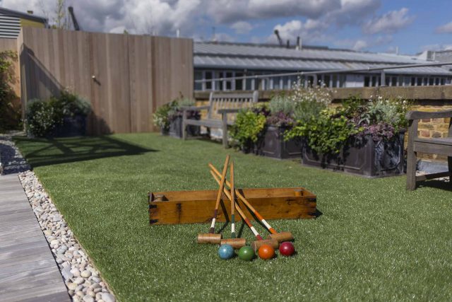 Roof terrace with decking, artificial level lawn and LED lighting design at New Concordia Wharf, highlight surfaces and architectural elements in the evenings.