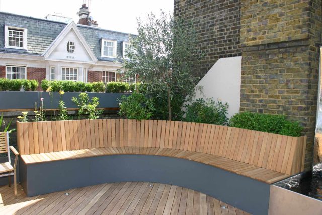 Contemporary Roof Terrace garden designer in Baker Street Marylebone, a stunning water feature curved bench cladded in iroko to create an illusion of space.