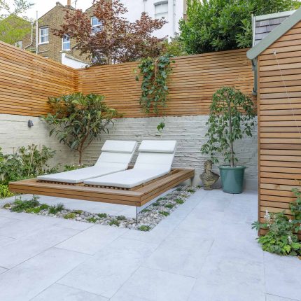 Garden design Vauxhall South London outdoor space, hidden LED strip lighting, polished white pebbles, porcelain paving steps tiles stand slatted cedar trellis.
