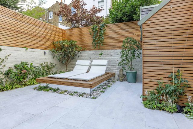 Garden design Vauxhall South London outdoor space, hidden LED strip lighting, polished white pebbles, porcelain paving steps tiles stand slatted cedar trellis.