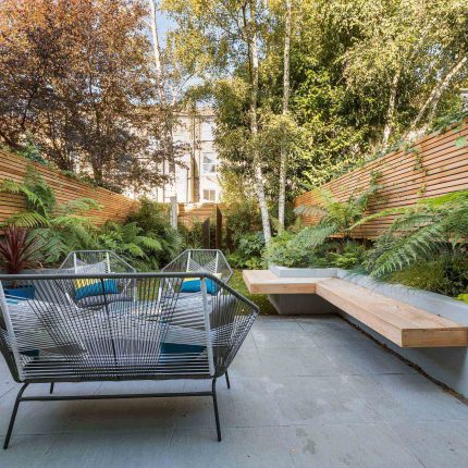 Small, contemporary garden in Islington, designed by Simon Ronan and constructed by The Garden Builders, flanking the terrace are raised beds, floating benches.
