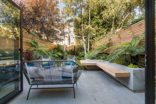 Small, contemporary garden in Islington, designed by Simon Ronan and constructed by The Garden Builders, flanking the terrace are raised beds, floating benches.