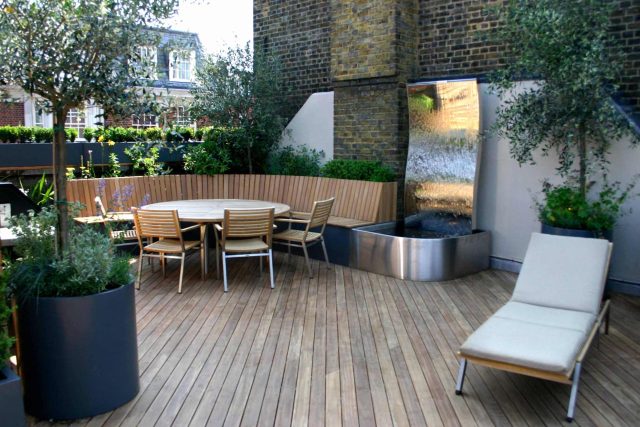 Contemporary Roof Terrace garden designer in Baker Street Marylebone, a stunning water feature curved bench cladded in iroko to create an illusion of space.