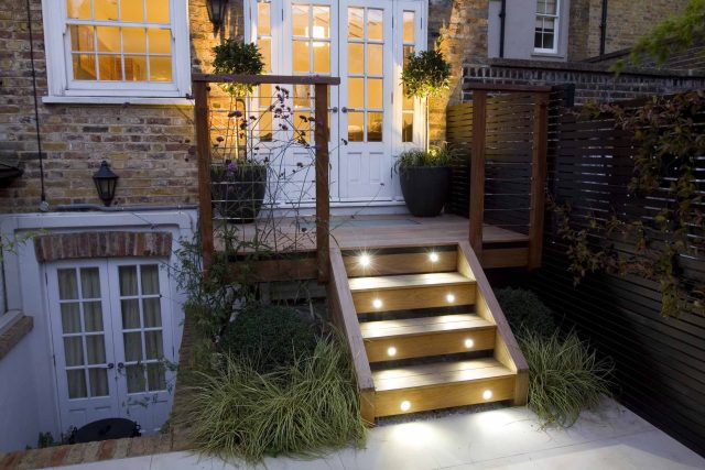 Outdoor room in Sloane Square Chelsea with Gloster exterior furniture and lighting and timber decking, roof terrace designer, sandstone paving raised beds.