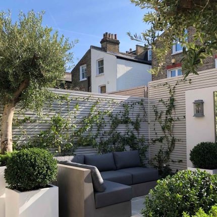 Wandsworth Garden designer initials Artificial Vertical Green Wall toward the rear of the garden breaks up the white of the adjoining trellis and creates space.