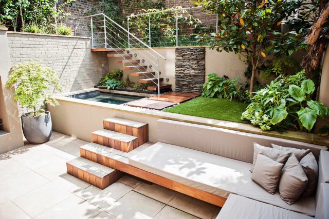 City design jacuzzi garden low maintenance with artificial lawn, stacked stone water wall BBQ Fire place feature, Hampstead Village, natural stone led lighting.