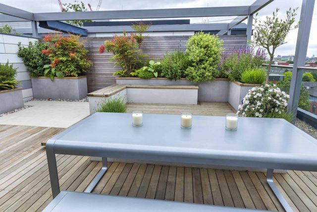 Roof Terrace garden Design for a penthouse apartment King's Cross development, expanse decking storage benches, planters, cedar deck seating area outdoor room.
