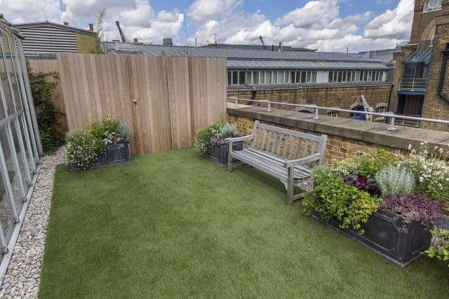 Roof terrace with decking, artificial level lawn and LED lighting design at New Concordia Wharf, highlight surfaces and architectural elements in the evenings.