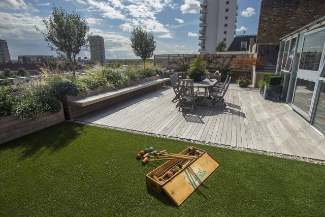 Roof terrace with decking, artificial level lawn and LED lighting design at New Concordia Wharf, highlight surfaces and architectural elements in the evenings.