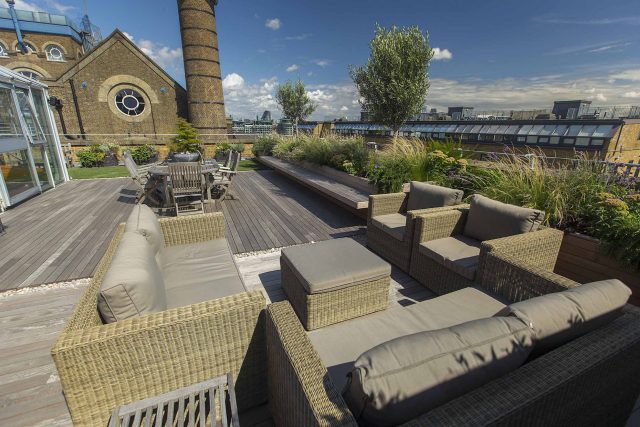 Roof terrace with decking, artificial level lawn and LED lighting design at New Concordia Wharf, highlight surfaces and architectural elements in the evenings.