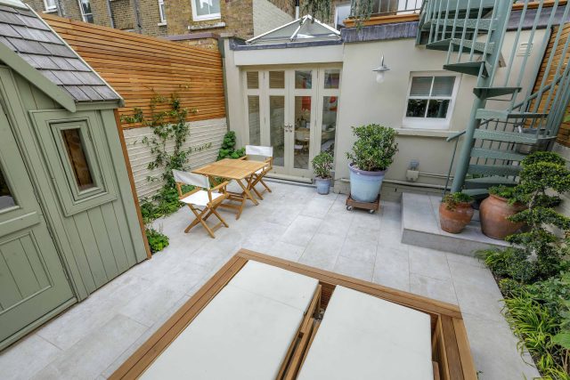 Garden design Vauxhall South London outdoor space, hidden LED strip lighting, polished white pebbles, porcelain paving steps tiles stand slatted cedar trellis.