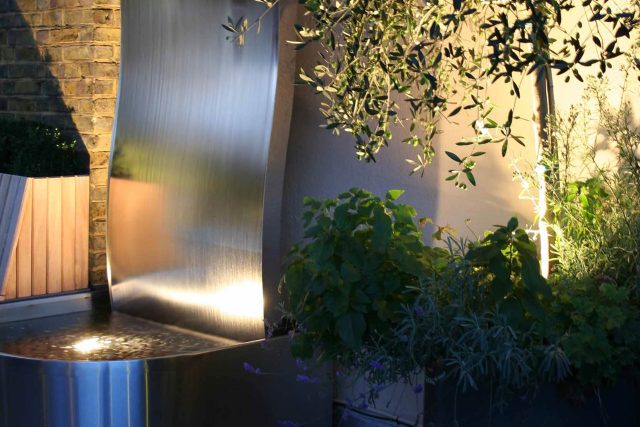 Contemporary Roof Terrace garden designer in Baker Street Marylebone, a stunning water feature curved bench cladded in iroko to create an illusion of space.