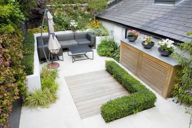 Outdoor room in Sloane Square Chelsea with Gloster exterior furniture and lighting and timber decking, roof terrace designer, sandstone paving raised beds.