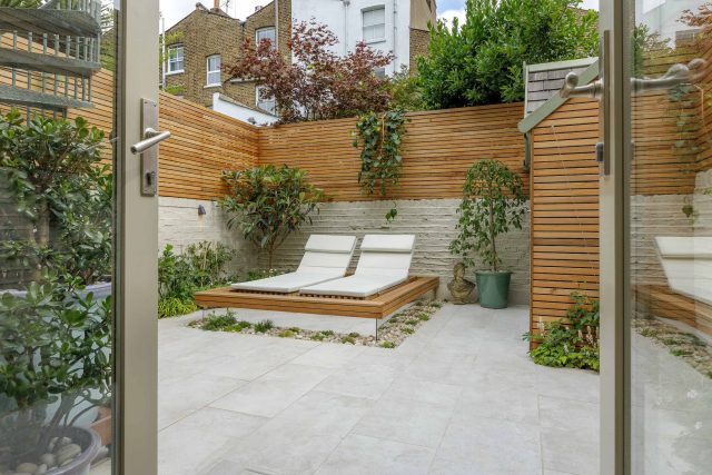 Garden design Vauxhall South London outdoor space, hidden LED strip lighting, polished white pebbles, porcelain paving steps tiles stand slatted cedar trellis.