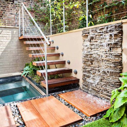 City design jacuzzi garden low maintenance with artificial lawn, stacked stone water wall BBQ Fire place feature, Hampstead Village, natural stone led lighting.