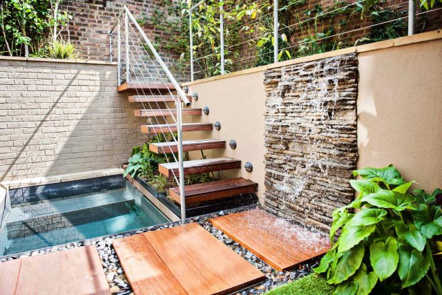 City design jacuzzi garden low maintenance with artificial lawn, stacked stone water wall BBQ Fire place feature, Hampstead Village, natural stone led lighting.