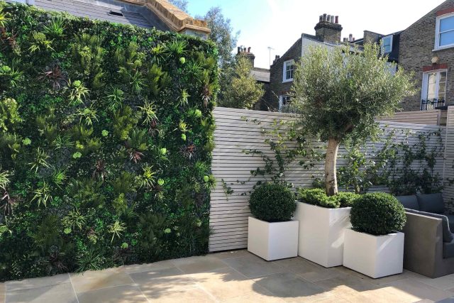 Wandsworth Garden designer initials Artificial Vertical Green Wall toward the rear of the garden breaks up the white of the adjoining trellis and creates space.