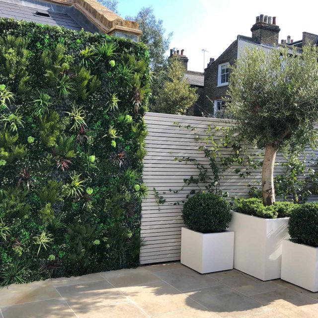 Wandsworth Garden designer initials Artificial Vertical Green Wall toward the rear of the garden breaks up the white of the adjoining trellis and creates space.