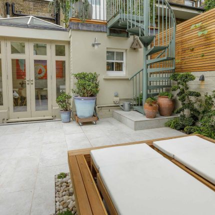 Garden design Vauxhall South London outdoor space, hidden LED strip lighting, polished white pebbles, porcelain paving steps tiles stand slatted cedar trellis.