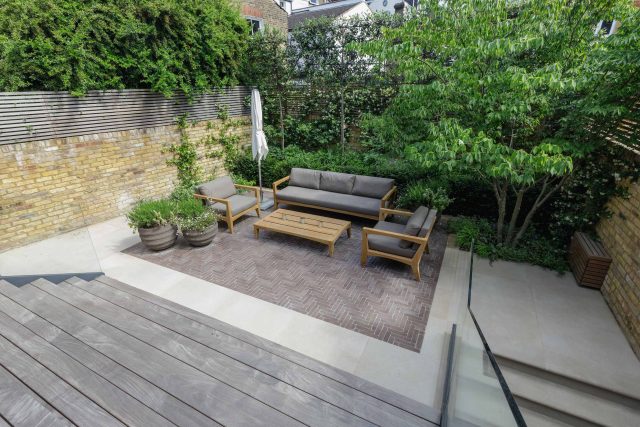 Courtyard Garden Design with an elegant walled space with Yorkstone work Fulham by The Garden Builders, canopy shade for a central lounge planted seating area.