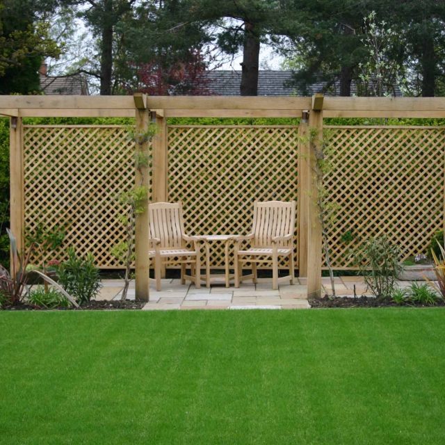 Water Feature Garden design Surrey overgrown woodland space in Surrey with outdoor Hunza lighting designers mature planting, circular paving, cedar pergola.