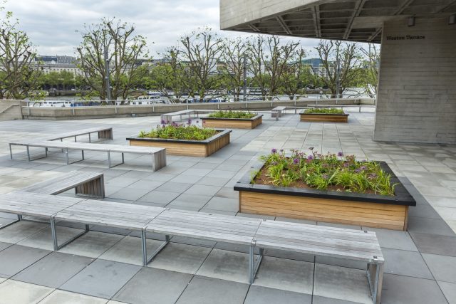 A concrete terrace with wooden benches on the brutalist South Bank in London.