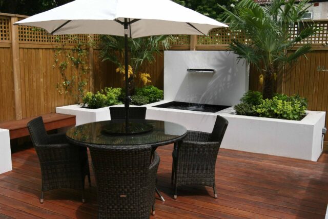 Decking design london elegant walled outdoor entertaining space Wimbledon South West London, lush planting, cozy relaxing outdoor dining area, water feature.