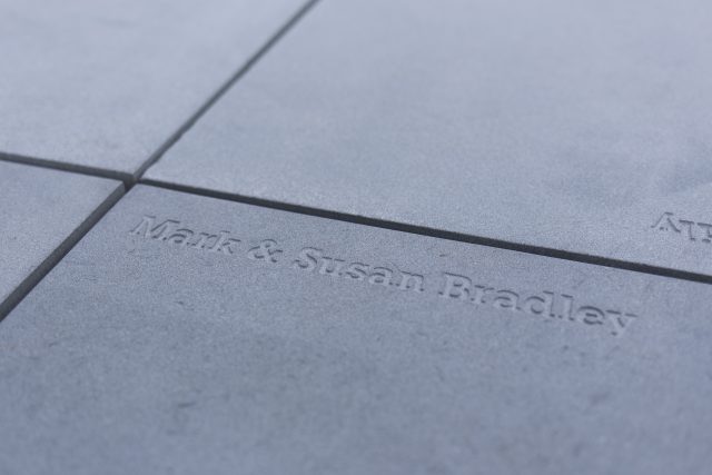 An engraved stone paver featuring a commemorative donor plaque inscription.