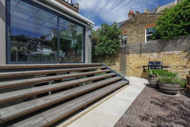 Courtyard Garden Design with an elegant walled space with Yorkstone work Fulham by The Garden Builders, canopy shade for a central lounge planted seating area.