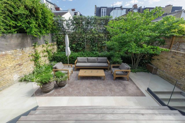Courtyard Garden Design with an elegant walled space with Yorkstone work Fulham by The Garden Builders, canopy shade for a central lounge planted seating area.