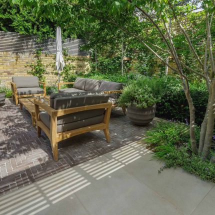 Courtyard Garden Design with an elegant walled space with Yorkstone work Fulham by The Garden Builders, canopy shade for a central lounge planted seating area.