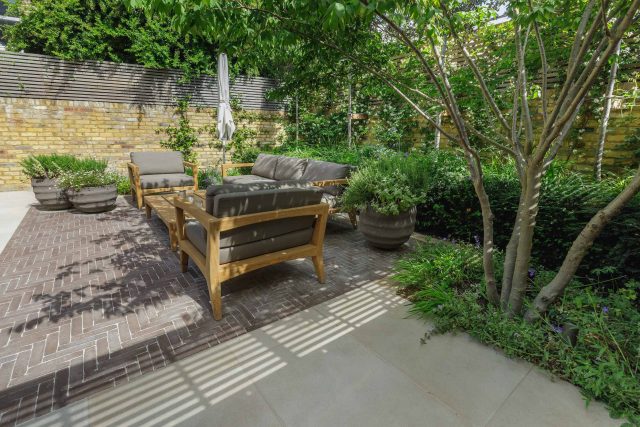 Courtyard Garden Design with an elegant walled space with Yorkstone work Fulham by The Garden Builders, canopy shade for a central lounge planted seating area.