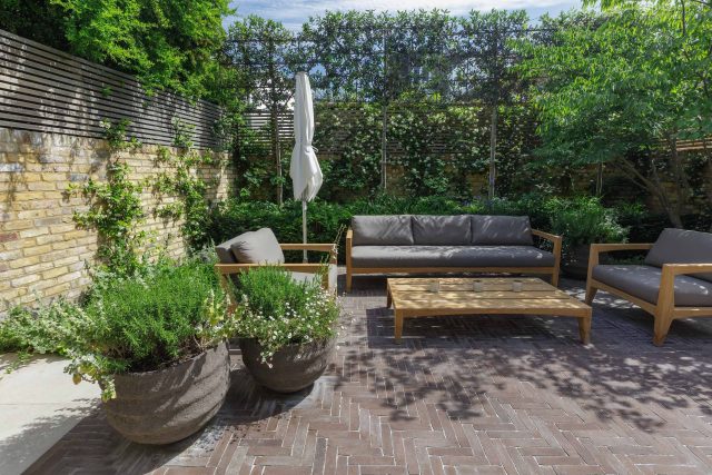 Courtyard Garden Design with an elegant walled space with Yorkstone work Fulham by The Garden Builders, canopy shade for a central lounge planted seating area.