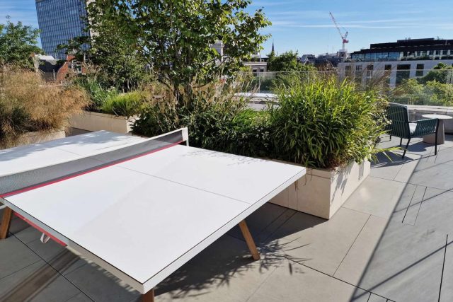 A ping pong table and stone planters on a modern London rooftop terrace.